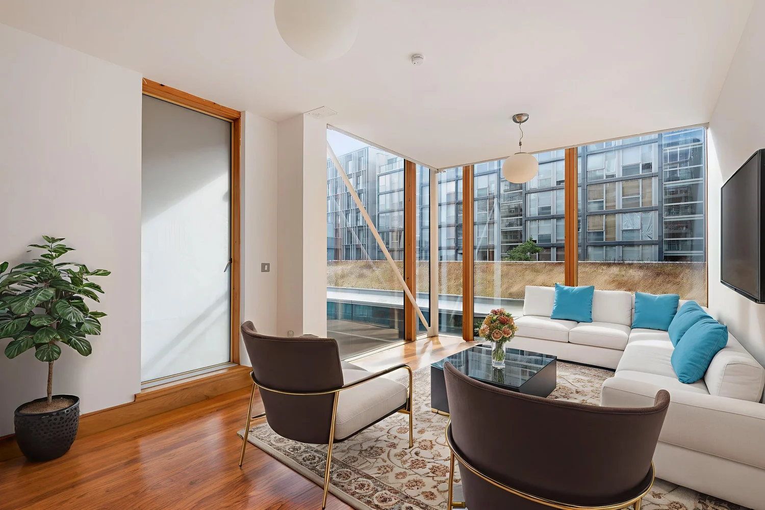 Apartment living room shown furnished, overlooking a neighbouring block
